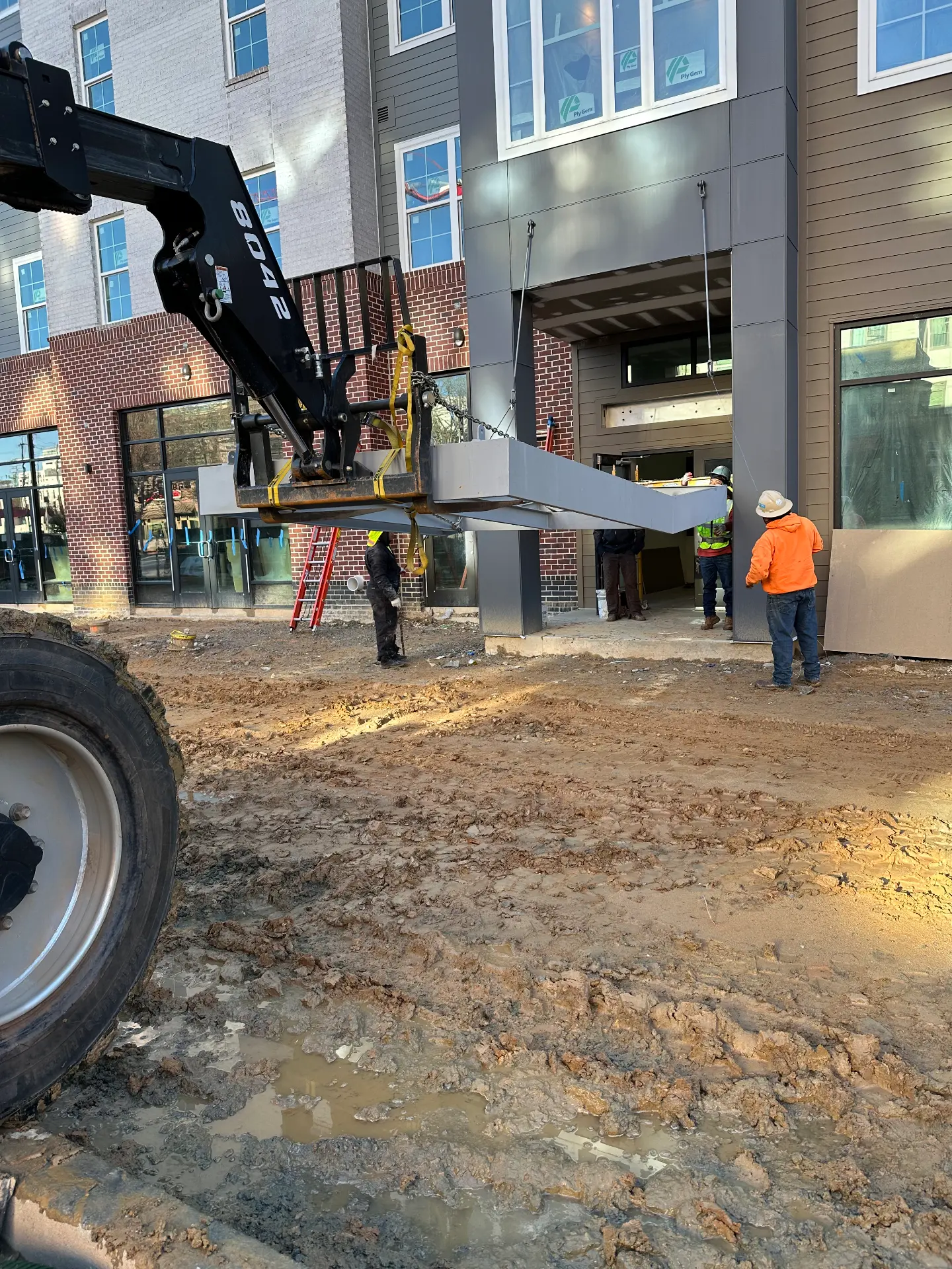 Crew setting a fabricated steel component with a telehandler