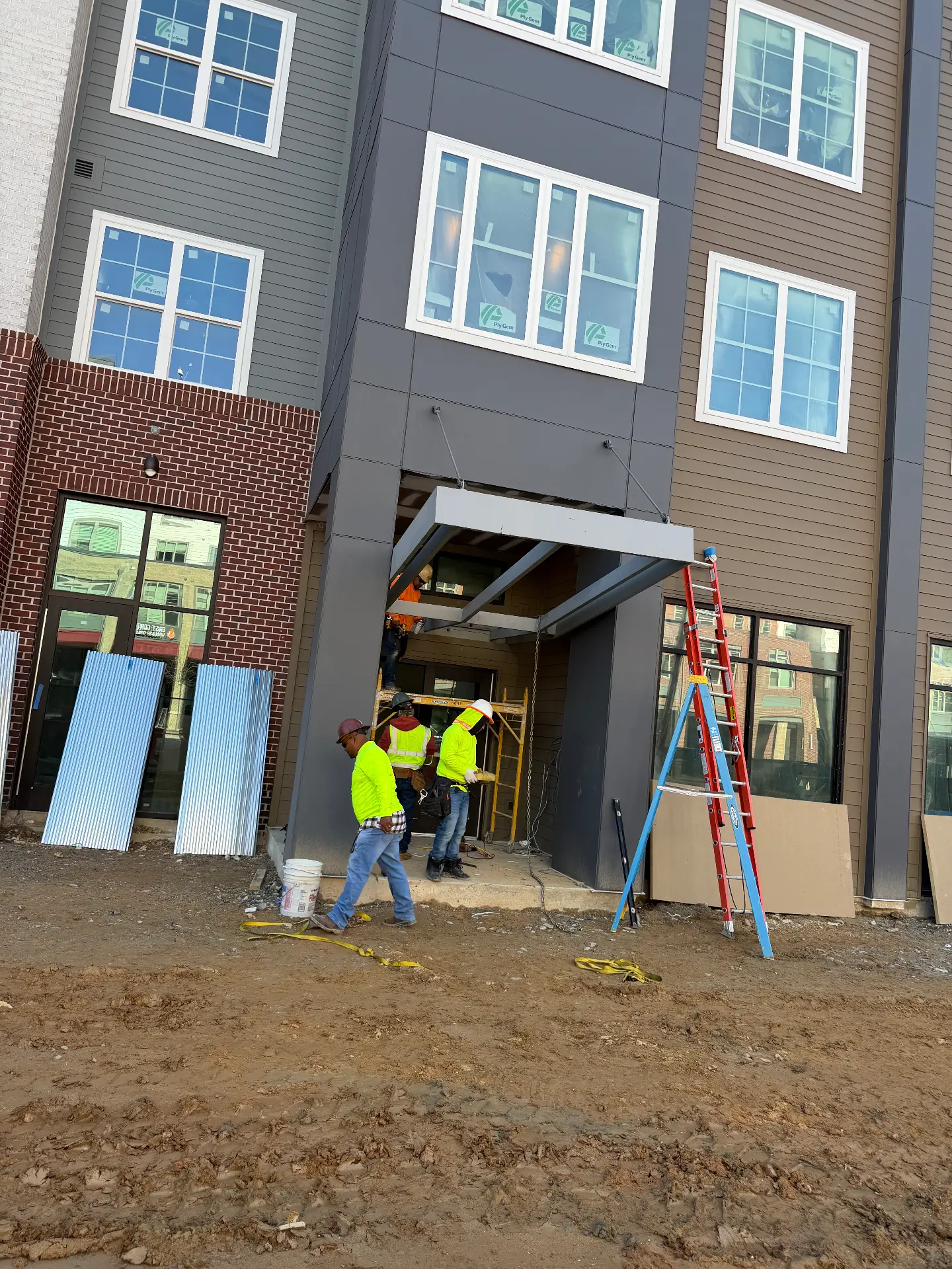Crew installing a steel entrance canopy on an apartment building